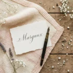 Pastel baby blanket with a hand-lettered name card on a wooden table